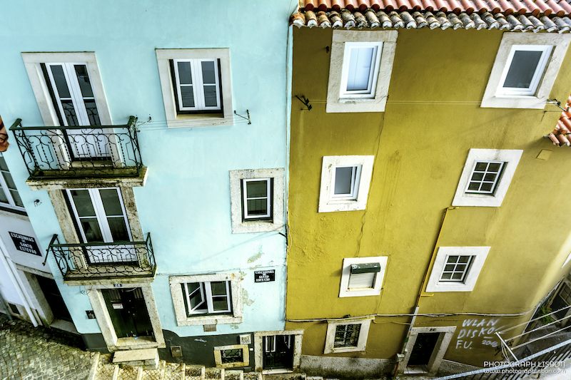 Turquoise and mustard facades of Escadinhas de Santo Estêvão seen from above, Alfama, Lisbon.