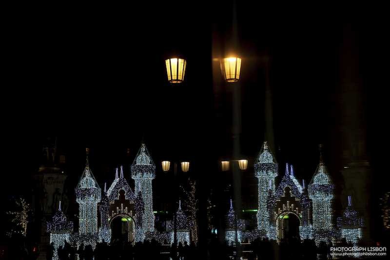 Illuminated castle installations and street lanterns at a winter light display in Lisbon.
